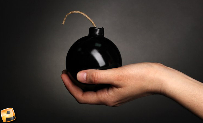 A hand holding a round black bomb with a fuse